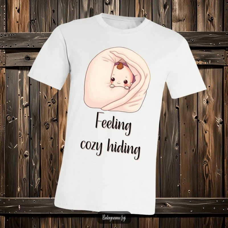 Funny baby blanket character peeking from behind a pillow, on a soft t-shirt. A cute and humorous graphic tee.